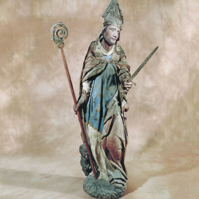 Sculpture représentant saint Théodule, tenant la crosse et le glaive, et accompagné du diablotin portant une cloche. Mélèze polychromé, 16e siècle © Musées cantonaux du Valais - Jean-Yves Glassey, Musée d’histoire du Valais