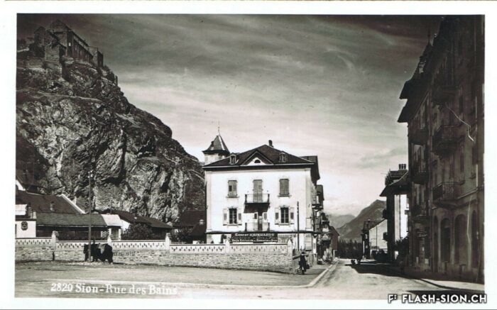 La place du Midi avant la construction du bâtiment « Les Rochers », et l’ancienne rue des Bains (actuelle rue du Scex), vers 1925 © Archives de la Ville de Sion
