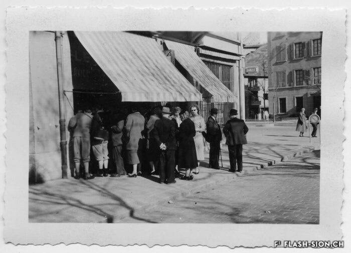 Passants curieux devant la vitrine du magasin Electra à la rue des Remparts, 17 avril 1958 © Archives de la Ville de Sion, fonds Michelotti, photo Mussler
