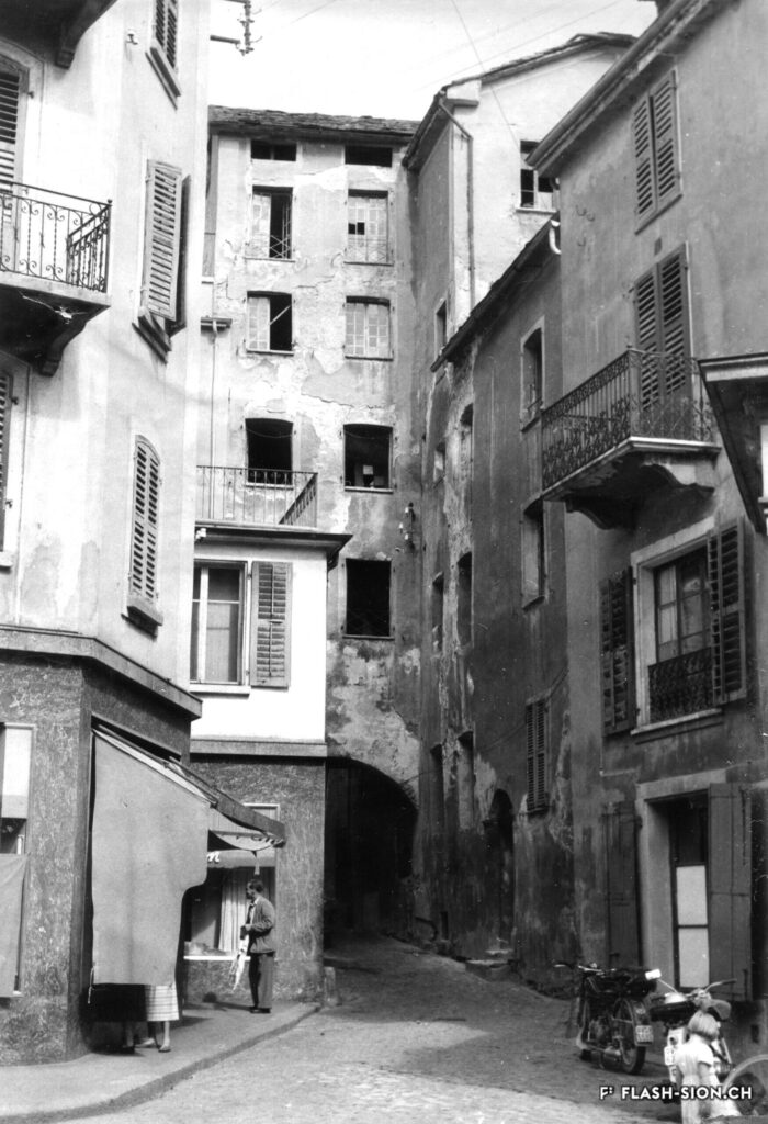 Entrée de la ruelle avec le bâtiment Garbaccia, vue depuis le Grand-Pont, 1950 env. © Archives de la Ville de Sion