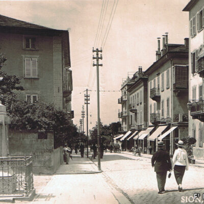 Rue de Lausanne et colonne baromètre « offerte » par la Société de musique « La Valéria » en 1890 à la ville, env. 1920 © Ed. Photo-Hall – Sion, Archives de la Ville de Sion
