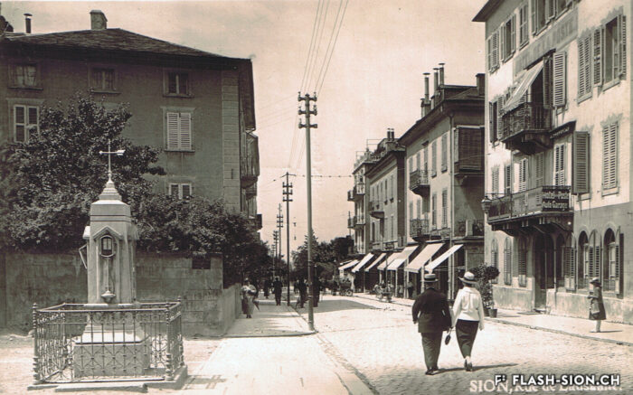Rue de Lausanne et colonne baromètre « offerte » par la Société de musique « La Valéria » en 1890 à la ville, env. 1920 © Ed. Photo-Hall – Sion, Archives de la Ville de Sion