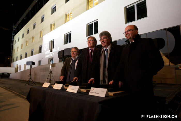 Inauguration du bâtiment d'Energypolis, Marcel Maurer, Jean-Michel Cina, Patrick Aebischer et Grégoire Dussex posant devant le bâtiment éclairé, 19.12.2014 © Claude Coeudevez, Archives de la Ville de Sion