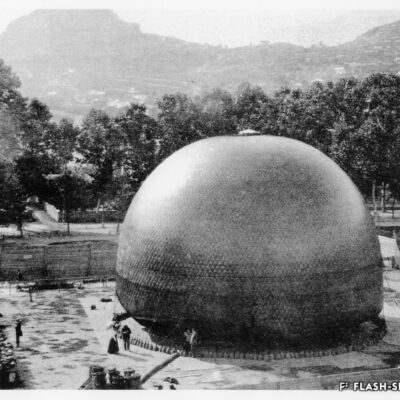 Le « WEGA » lors du gonflement. En bas à gauche, on discerne le générateur d’hydrogène, à gauche le Prof. Forel donne des explications au public présent, 29 septembre 1898 © Forstadjunkt Schönenberger, reproduction Archives de la Ville de Sion