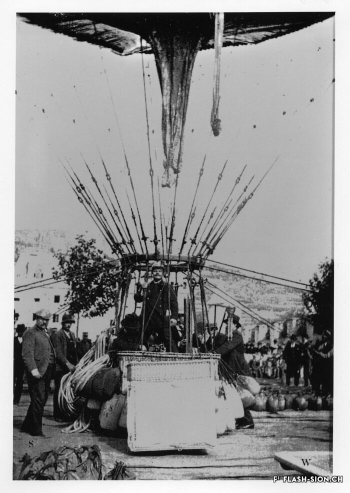 Le cercle de charge s’élève en l’air et les sacs de sable sont décrochés du filet et en partie utilisés pour lester la nacelle. Dans la nacelle, on distingue Edouard Spelterini, 1898 © Adrien Mercier fils, reproduction Archives de la Ville de Sion