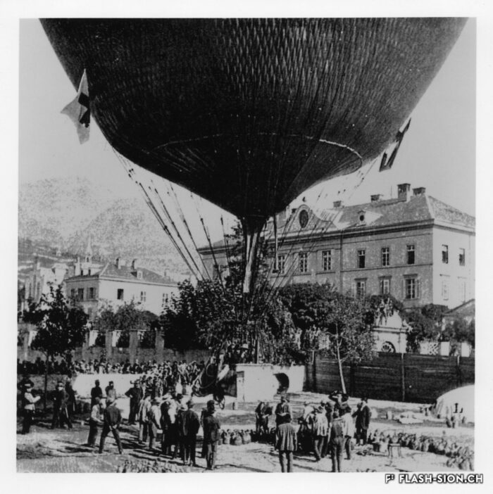 Les cordes retenant le cercle de charge au sol sont enlevées, l’aérostat flotte au-dessus du sol, 1898 © Adrien Mercier fils, reproduction Archives de la Ville de Sion