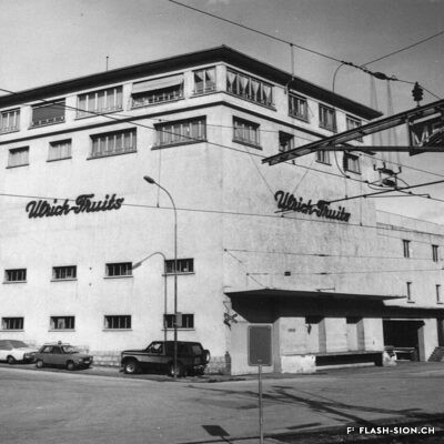 Varone Fruits et Maurice Gay SA sont repris par Ernest Ulrich qui agrandit les anciens dépôts Varone vers 1950. Bâtiment Ulrich Fruits, vers 1980, Archives de la Ville de Sion