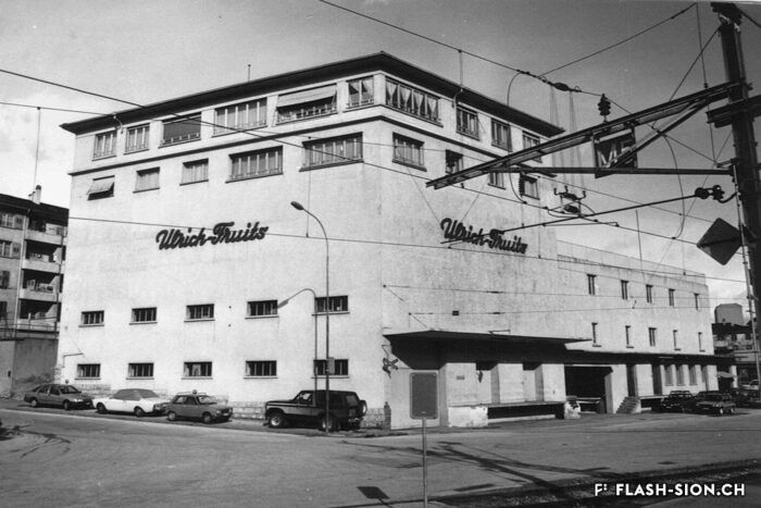 Varone Fruits et Maurice Gay SA sont repris par Ernest Ulrich qui agrandit les anciens dépôts Varone vers 1950. Bâtiment Ulrich Fruits, vers 1980, Archives de la Ville de Sion
